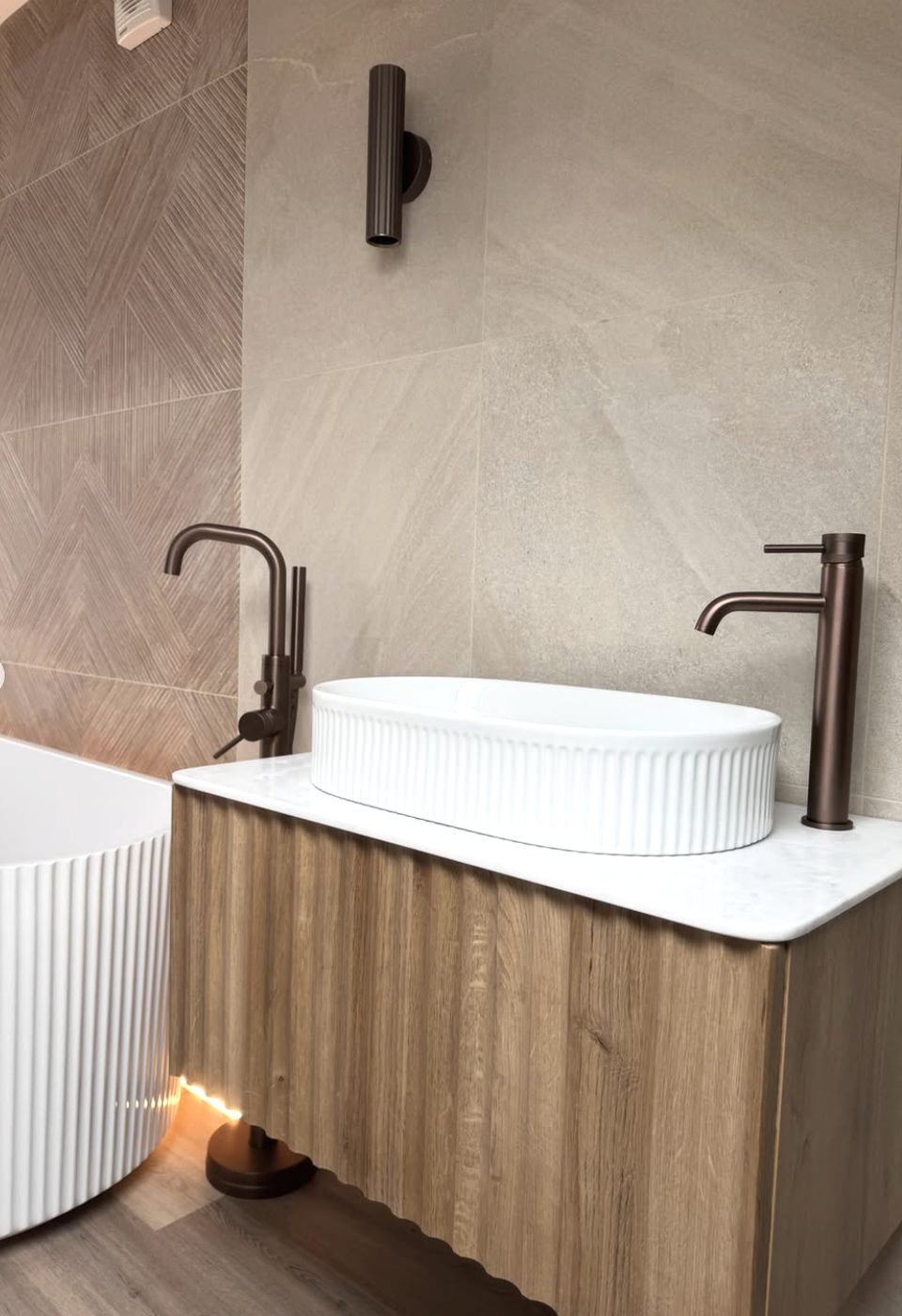 Fluted white vessel basin on a timber vanity with stone top and bronze tapware