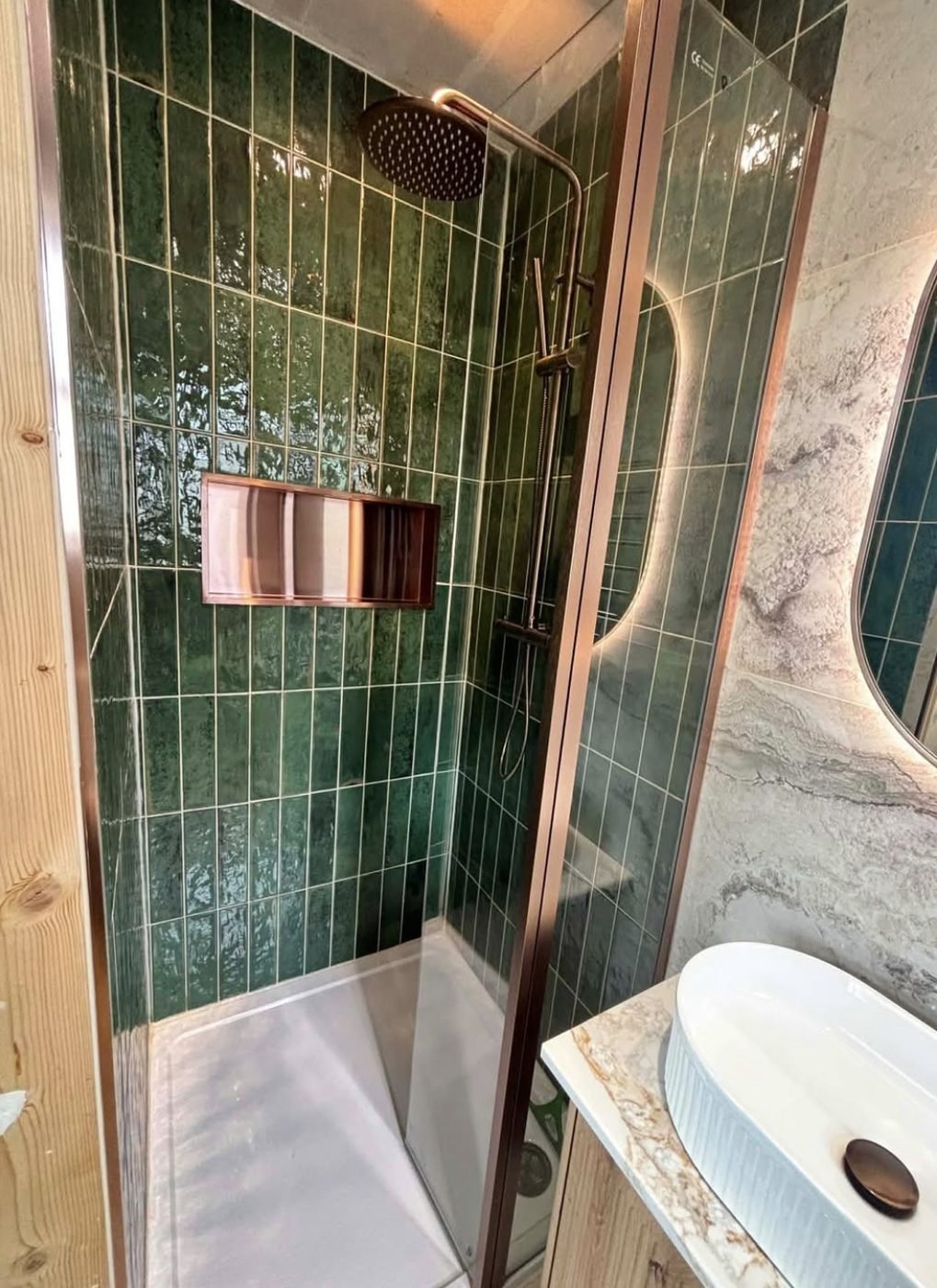 Green tiled shower enclosure with copper framed screen and rainfall shower head